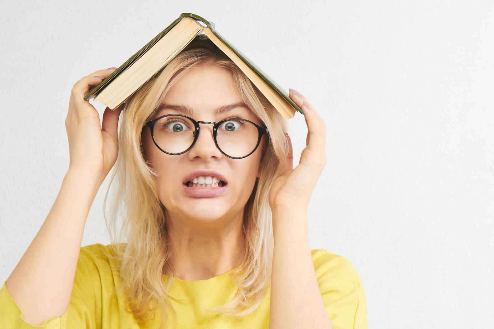 Stressed student holding a book over their head