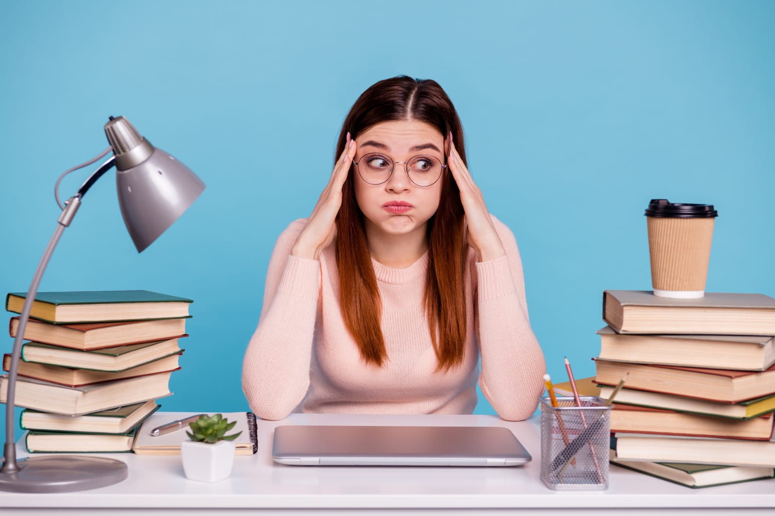 women at desk with books and coffee looking frustrated