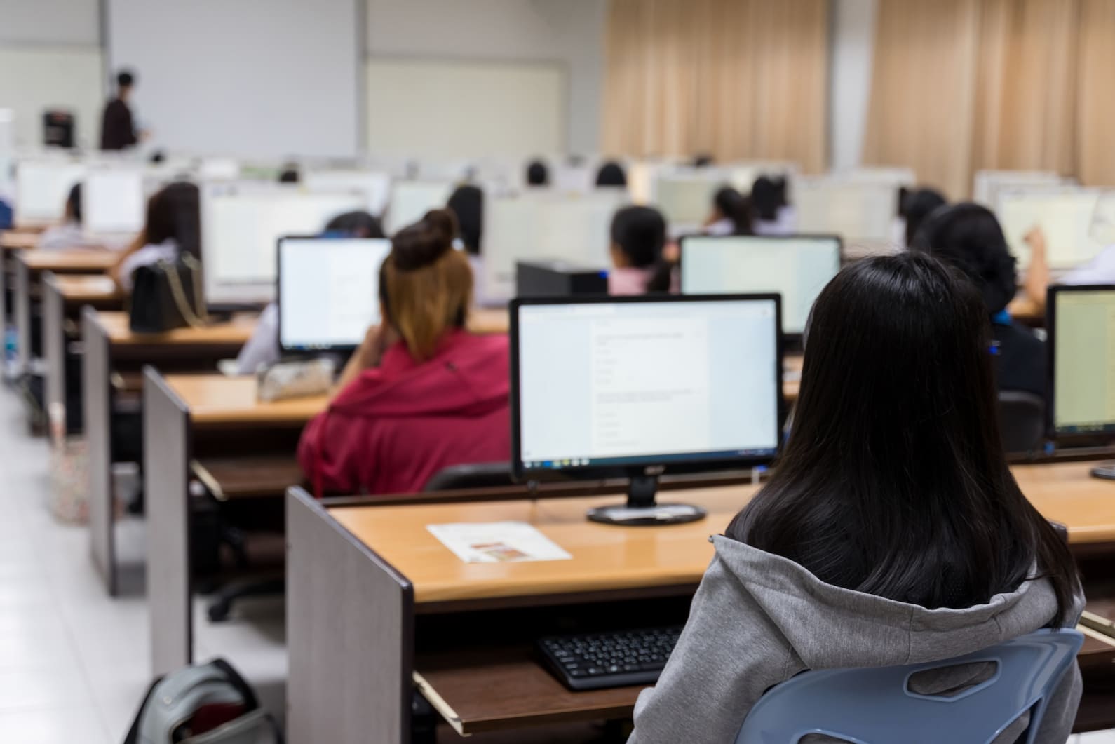 students in large classroom behind screens