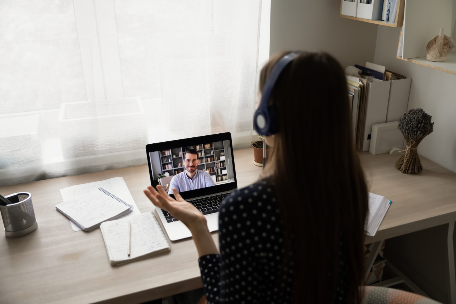 Woman with headset talking to a student via their laptop