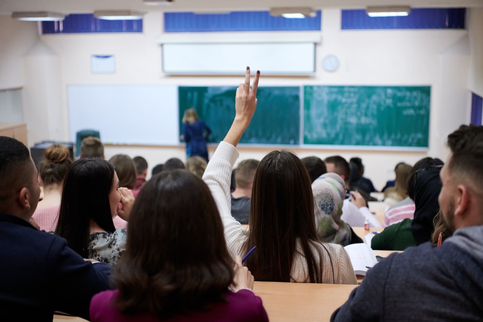 student with their hand up during class