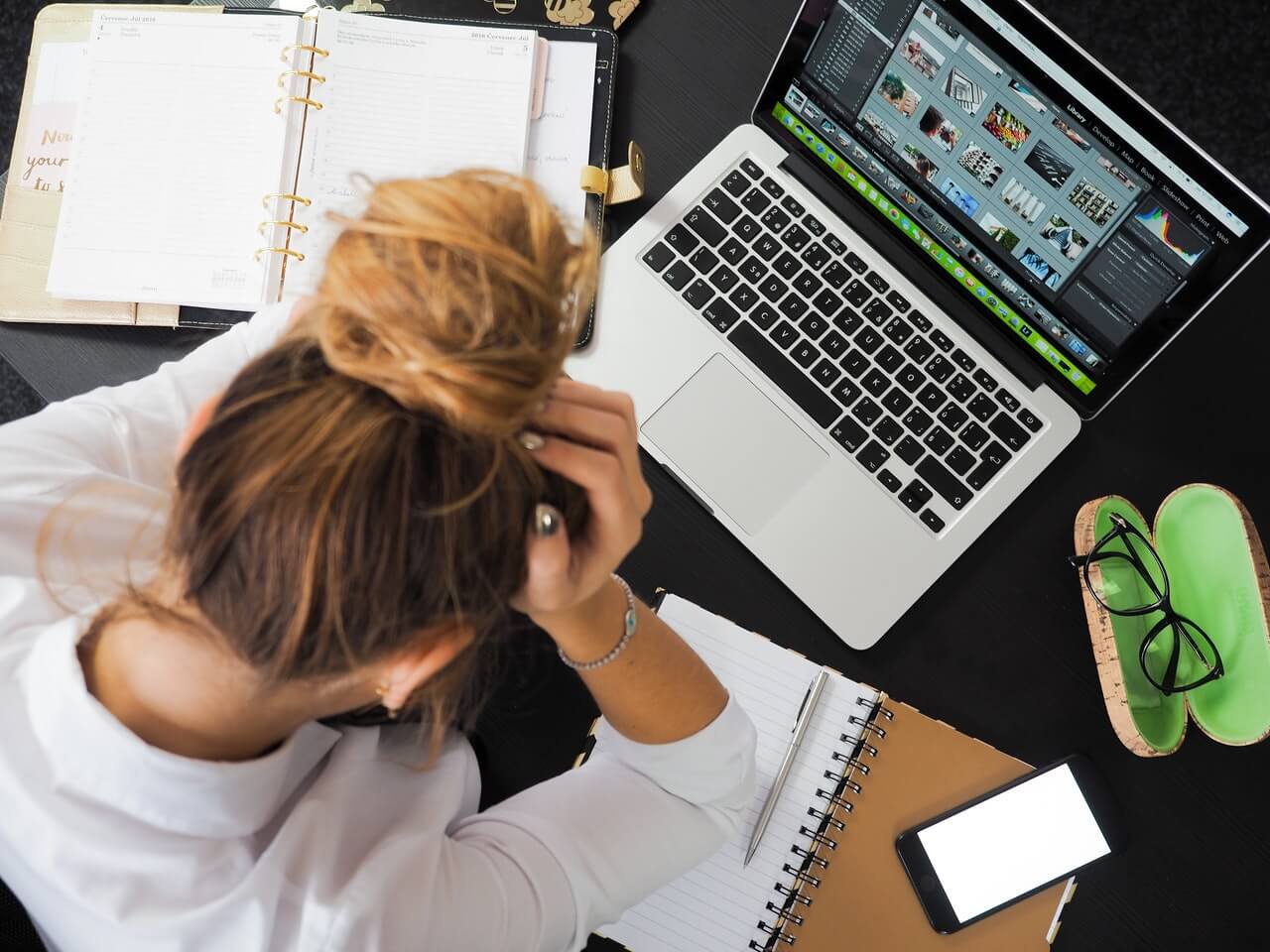 Woman with hand on her head looking down at a laptop