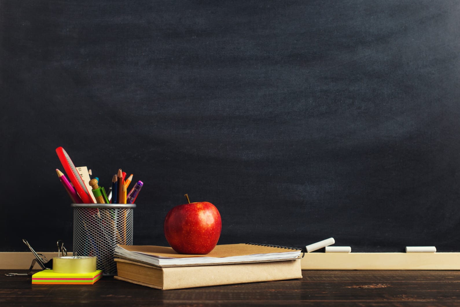 pencils and books and an apple sitting on a desk