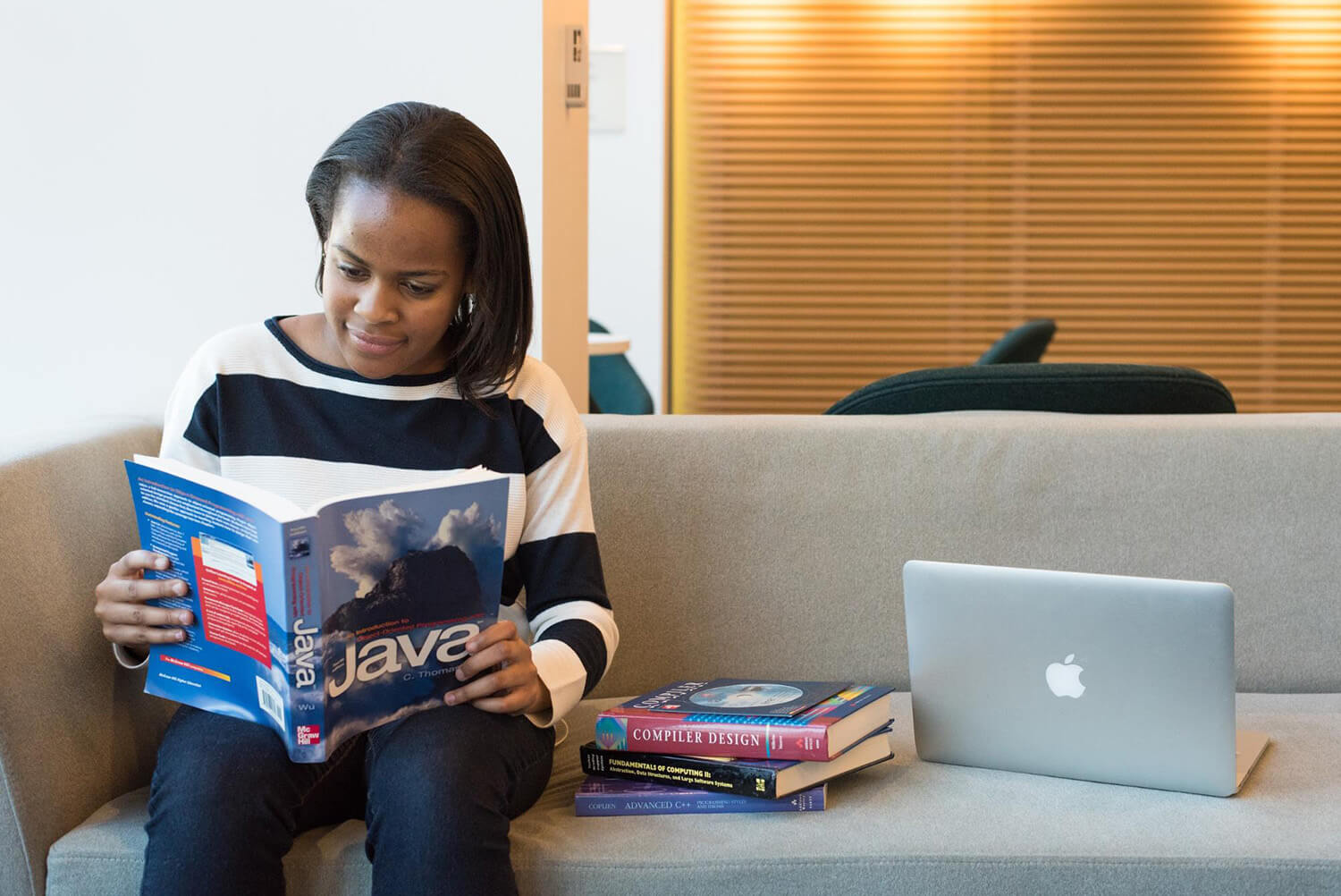 Student studying with a laptop and programming textbook