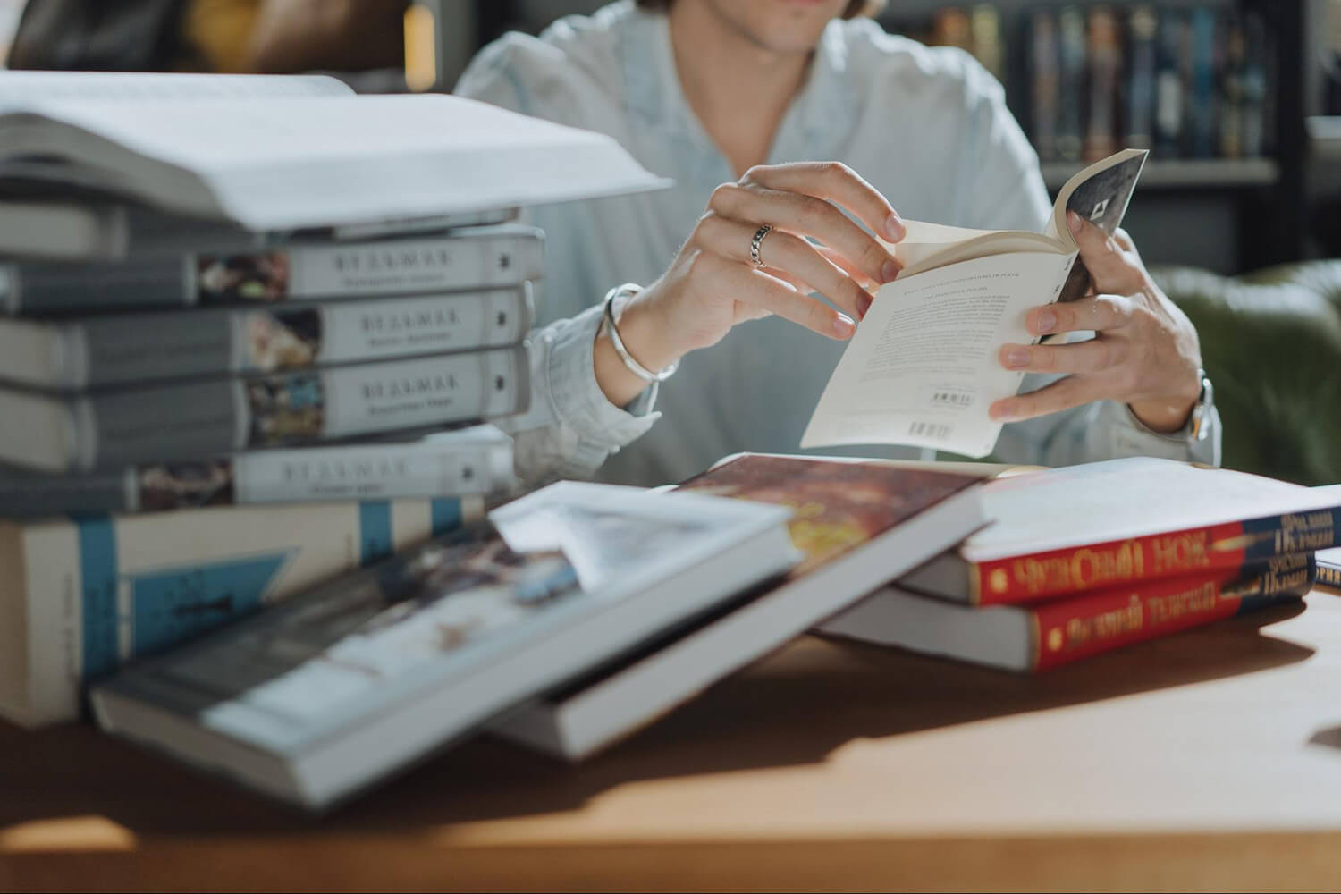 Student reading with a pile of books in the library