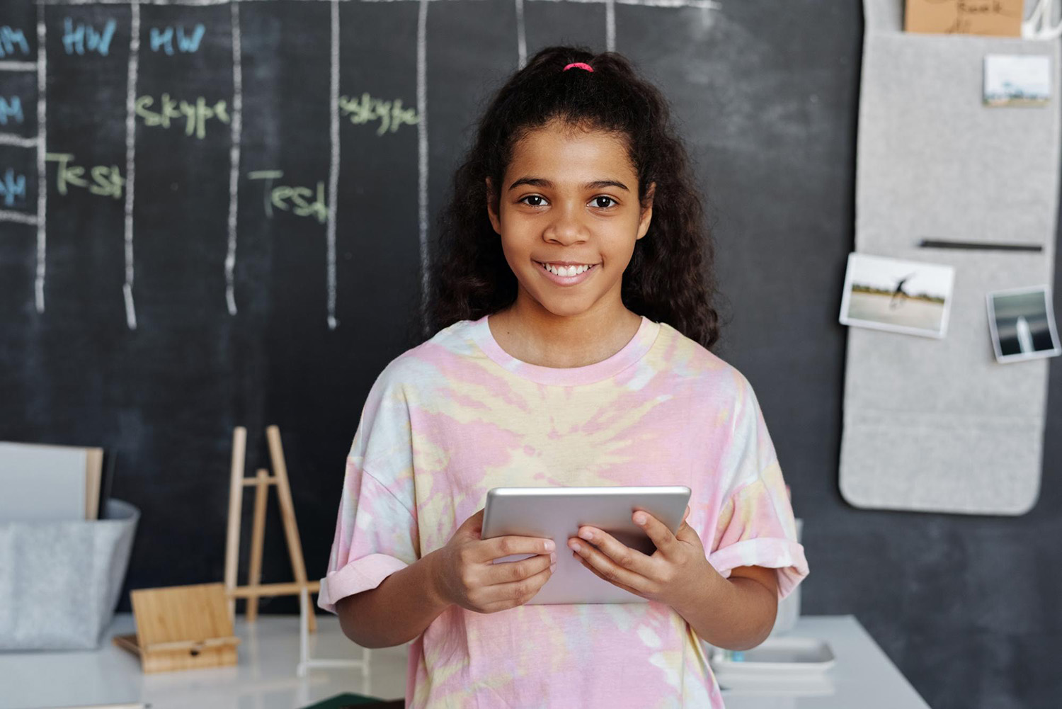 Student holding a tablet and smiling in a classroom