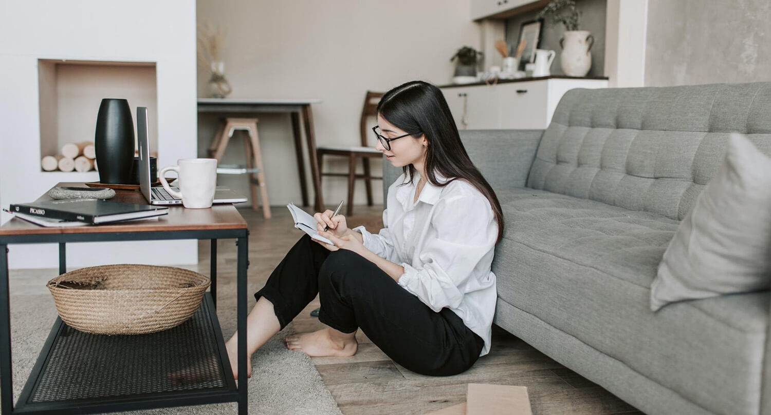 Student sitting on the floor at home writing