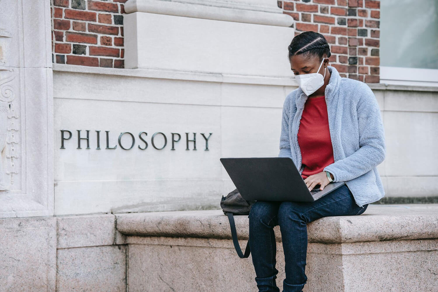 Student with a laptop sitting outside the philosophy building