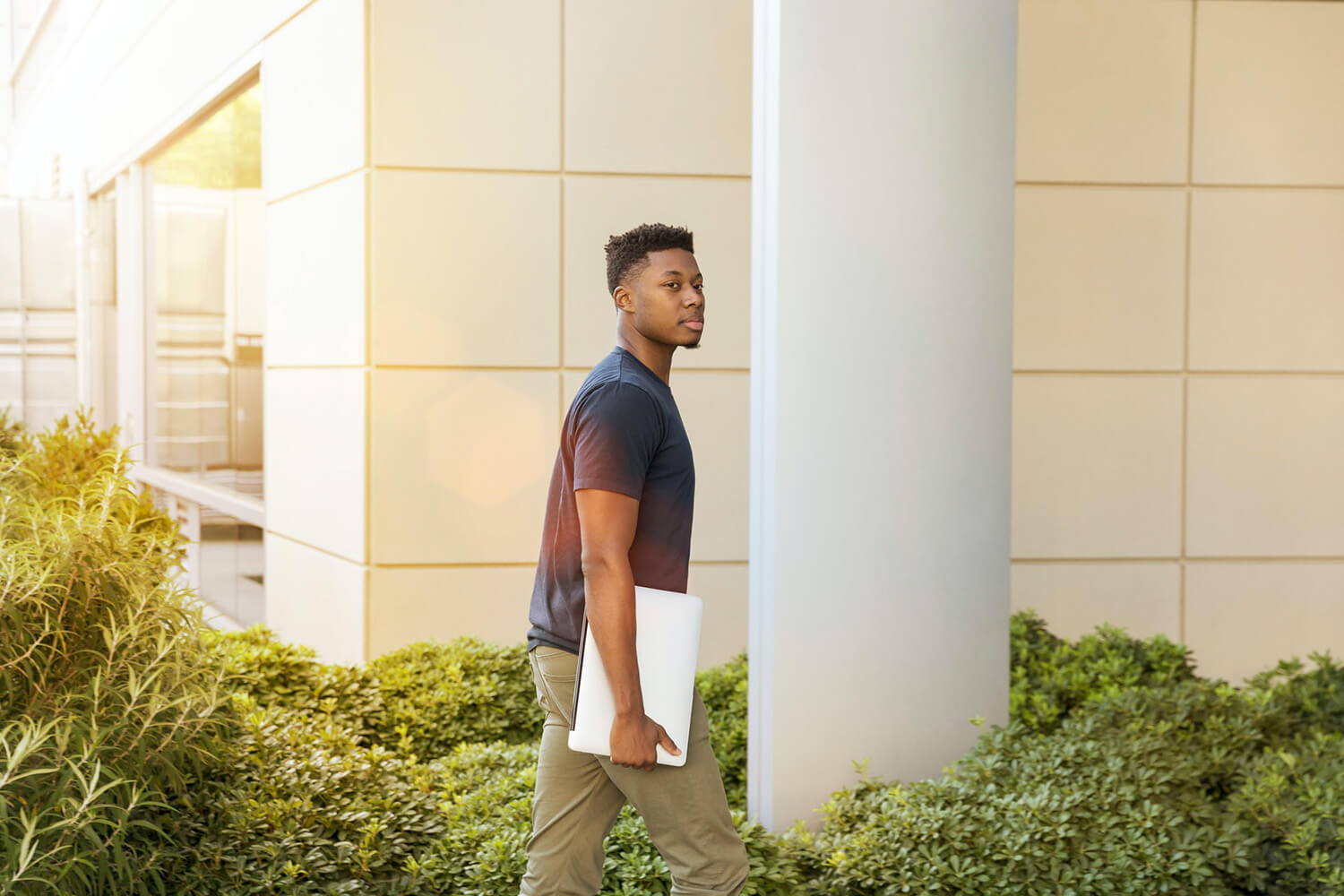 Student walking to class with a laptop