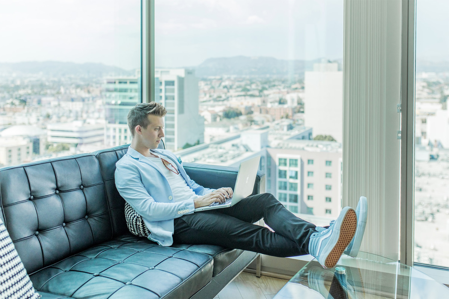 instructo sitting on a couch with their laptop reviewing a presentation