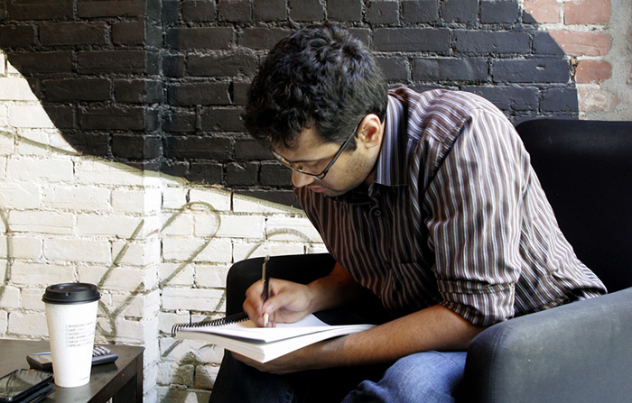 Man writing in notebook in cafe